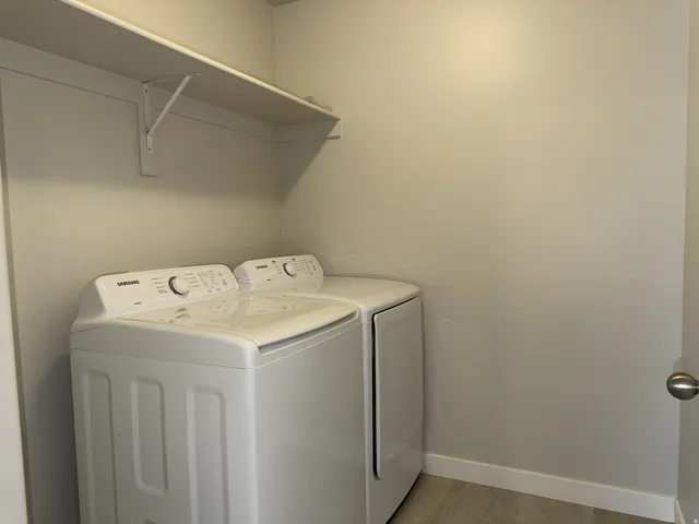 Dedicated utility area featuring a wall-mounted storage shelf and plank flooring