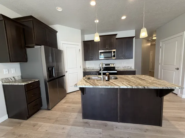 Kitchen featuring dark wood cabinetry, light wood-finish flooring, and granite countertops