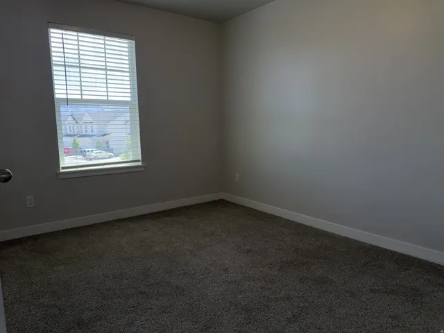 Carpeted room with a rectangular window featuring horizontal blinds