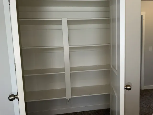 Built-in shelving unit featuring multiple adjustable shelves, a clean white finish, and a coordinating white baseboard
