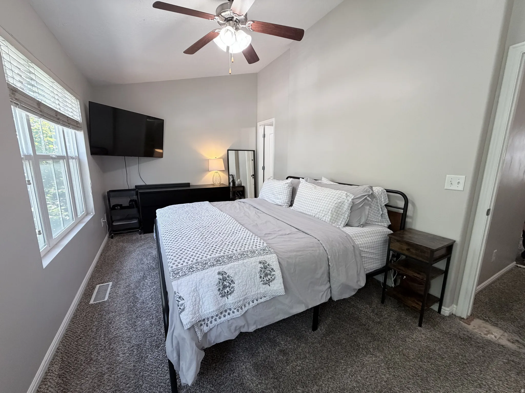 Bedroom featuring vaulted ceilings, ceiling fan with integrated lighting, twin windows with blinds, and neutral-toned carpeting