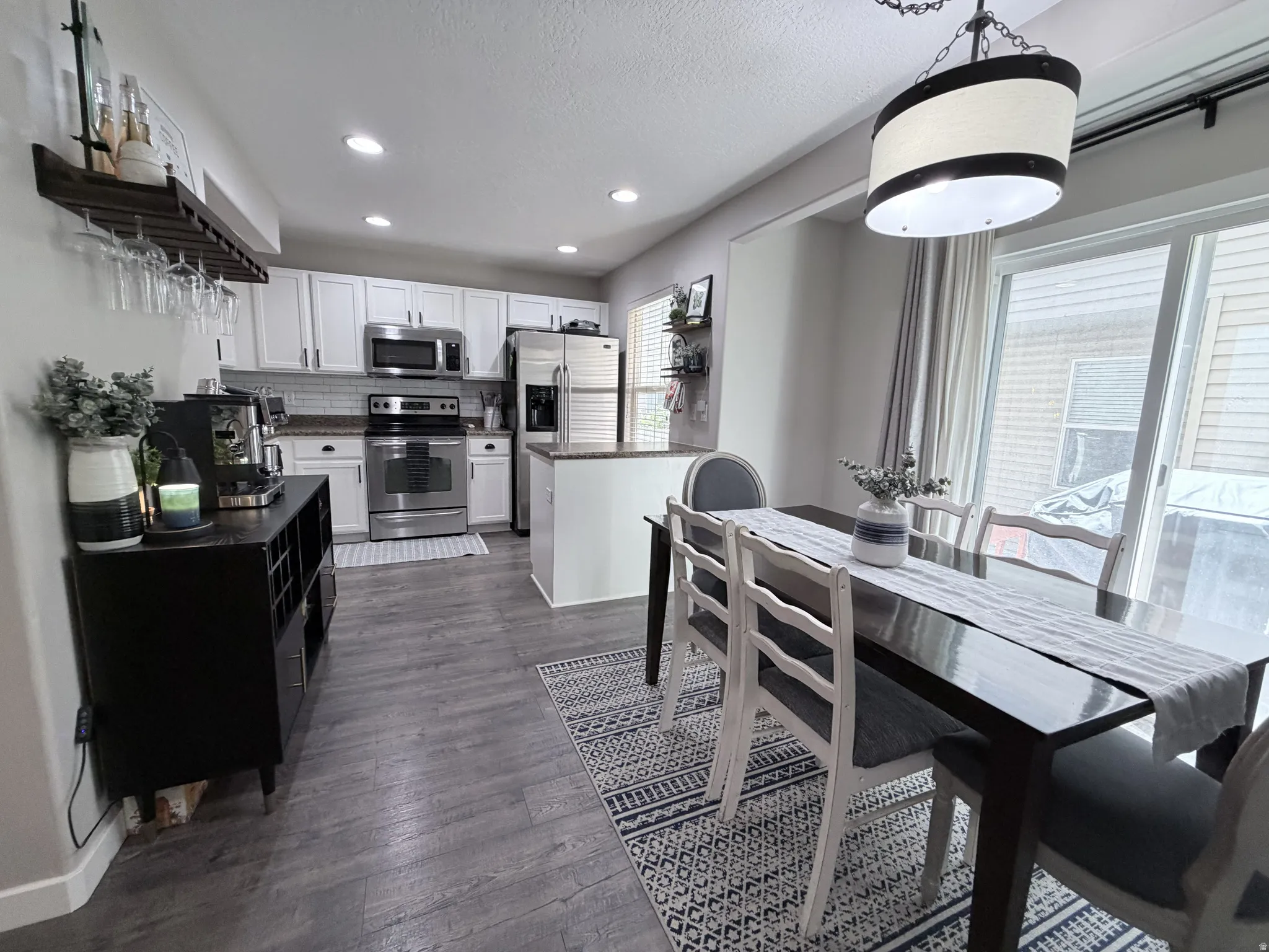 Open concept kitchen and dining area featuring light wood-finish flooring, stainless steel appliances, white cabinetry, and recessed lighting