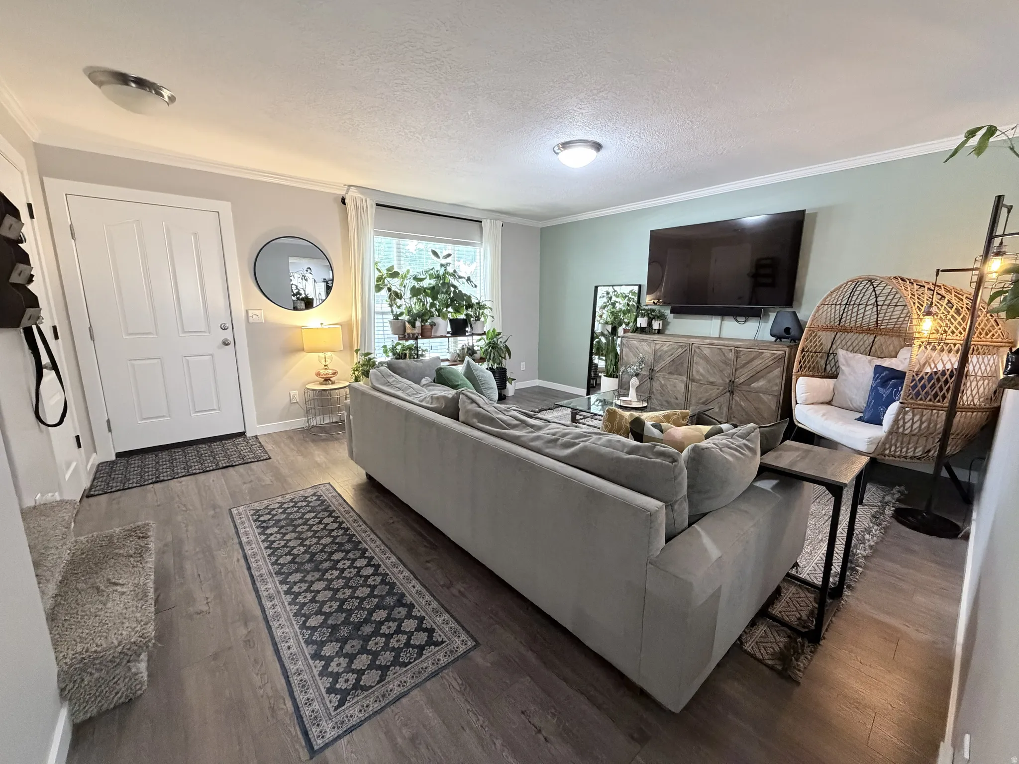 Open living area featuring wood-finish flooring, light-toned wall paint, white trim, and a large window with white blinds