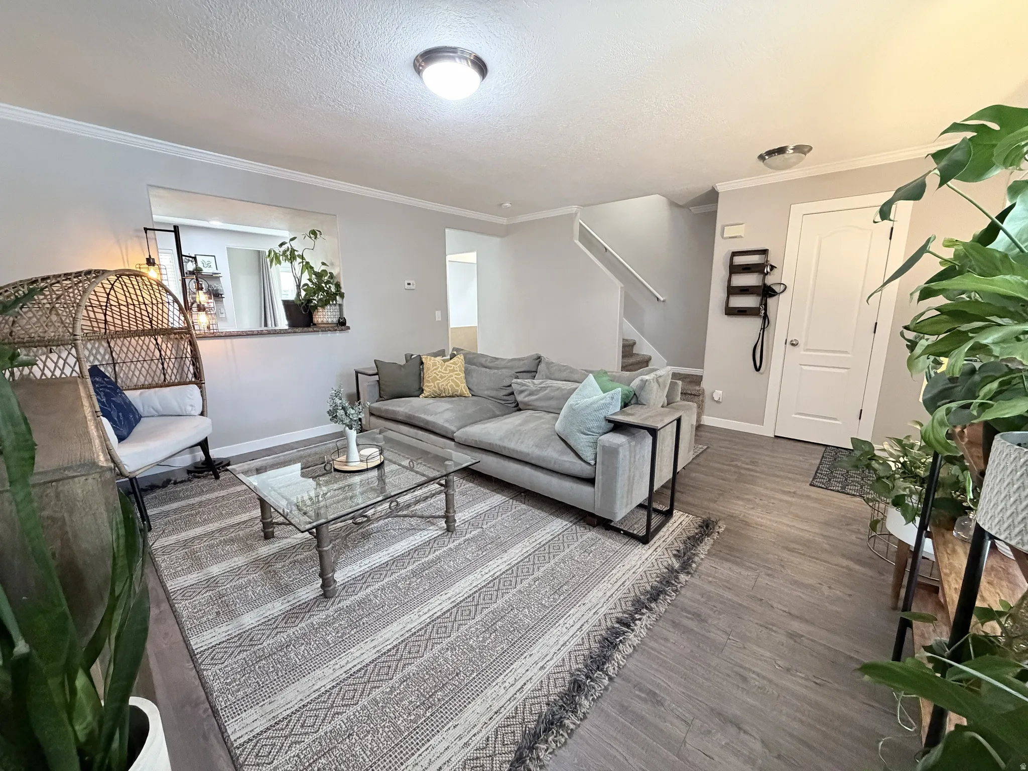 Open-concept living space featuring wood-finish flooring, a contemporary staircase with white risers, and a half-wall with a countertop