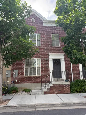 Brick facade residence featuring multiple windows, a prominent gable, a gabled roofline, and a concrete pathway leading to the entry