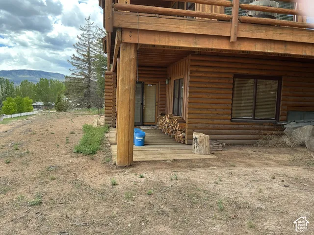 Log cabin exterior featuring a ground-level deck, upper-level balcony, and natural wood construction