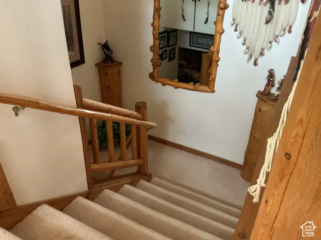 Staircase featuring wood-finish railings, wood-finish balusters, and carpeted treads