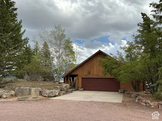 Wood-sided home featuring a concrete driveway, attached garage, and natural rock landscaping
