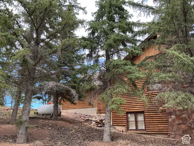 Log-sided exterior with a natural wood finish, featuring a stone foundation accent and mature evergreen trees