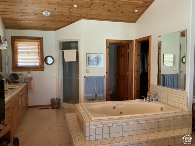 Spacious bathroom featuring a built-in jetted tub with tile surround, a corner glass-enclosed shower, and a dual-sink vanity with wood cabinetry