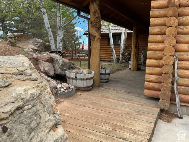 Log home exterior featuring a covered porch with plank flooring and natural wood structural elements