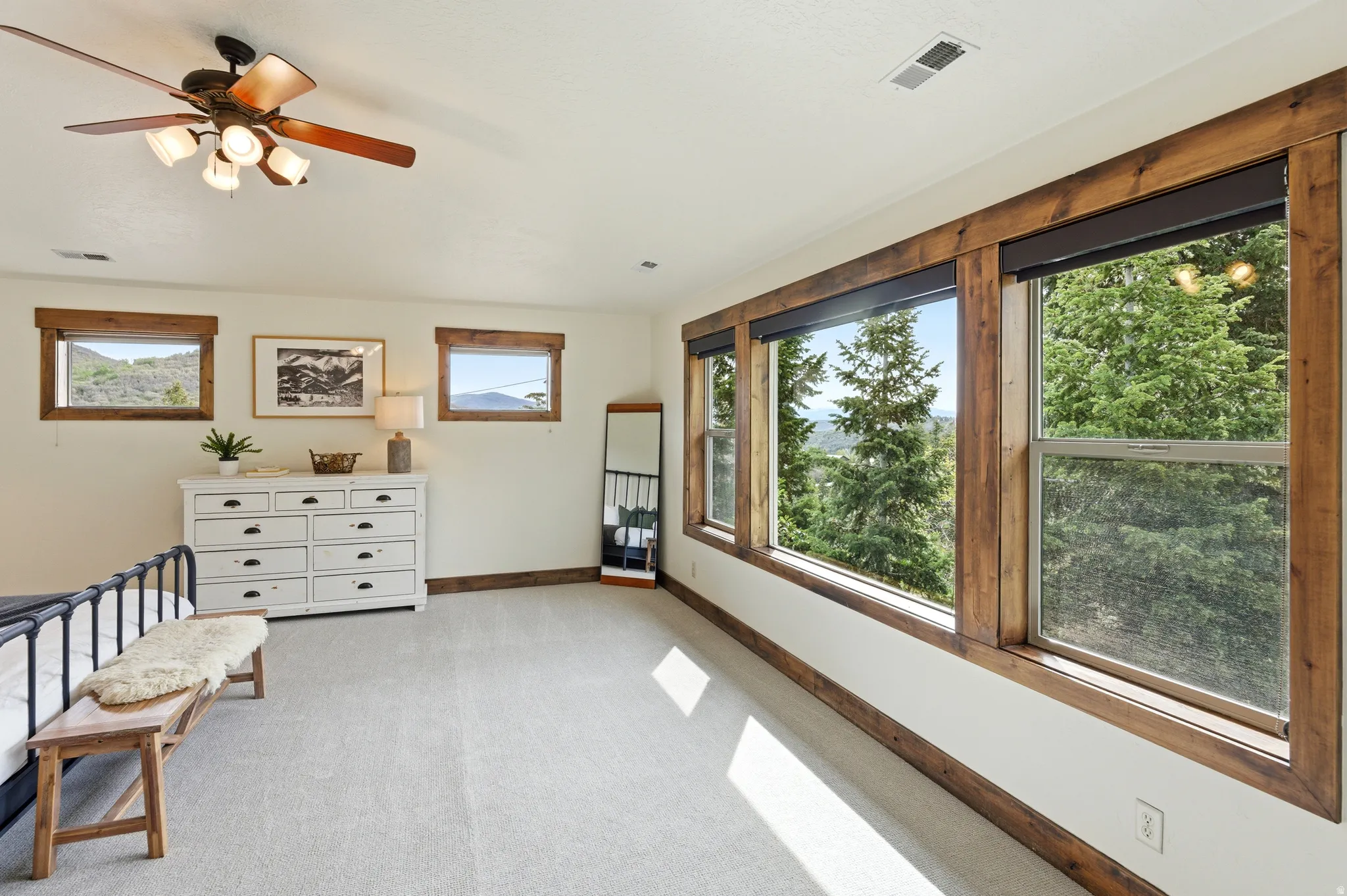 Large windows with natural wood trim framing exterior foliage