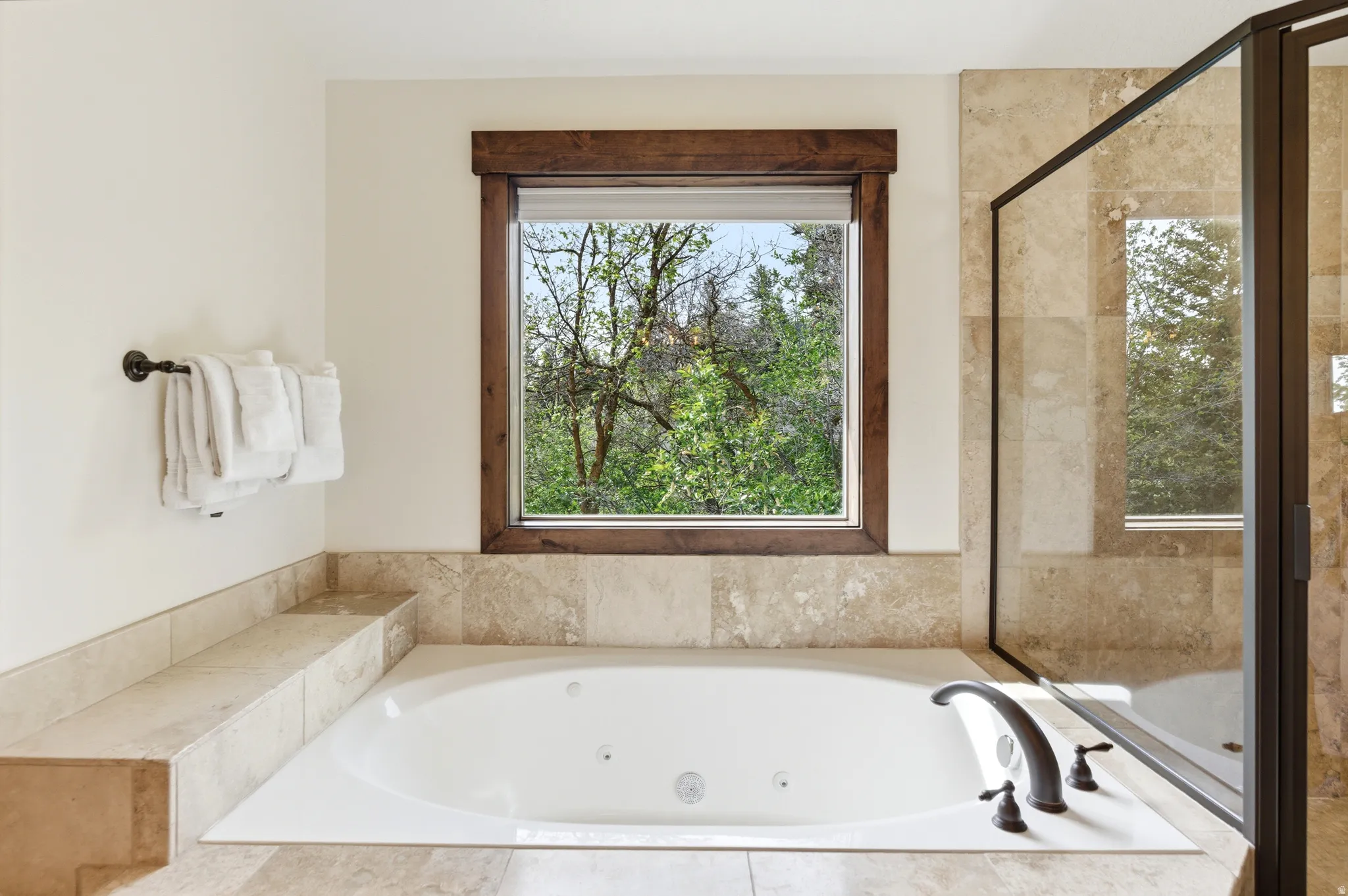 Built-in jetted tub with dark bronze fixtures, framed by natural wood window trim