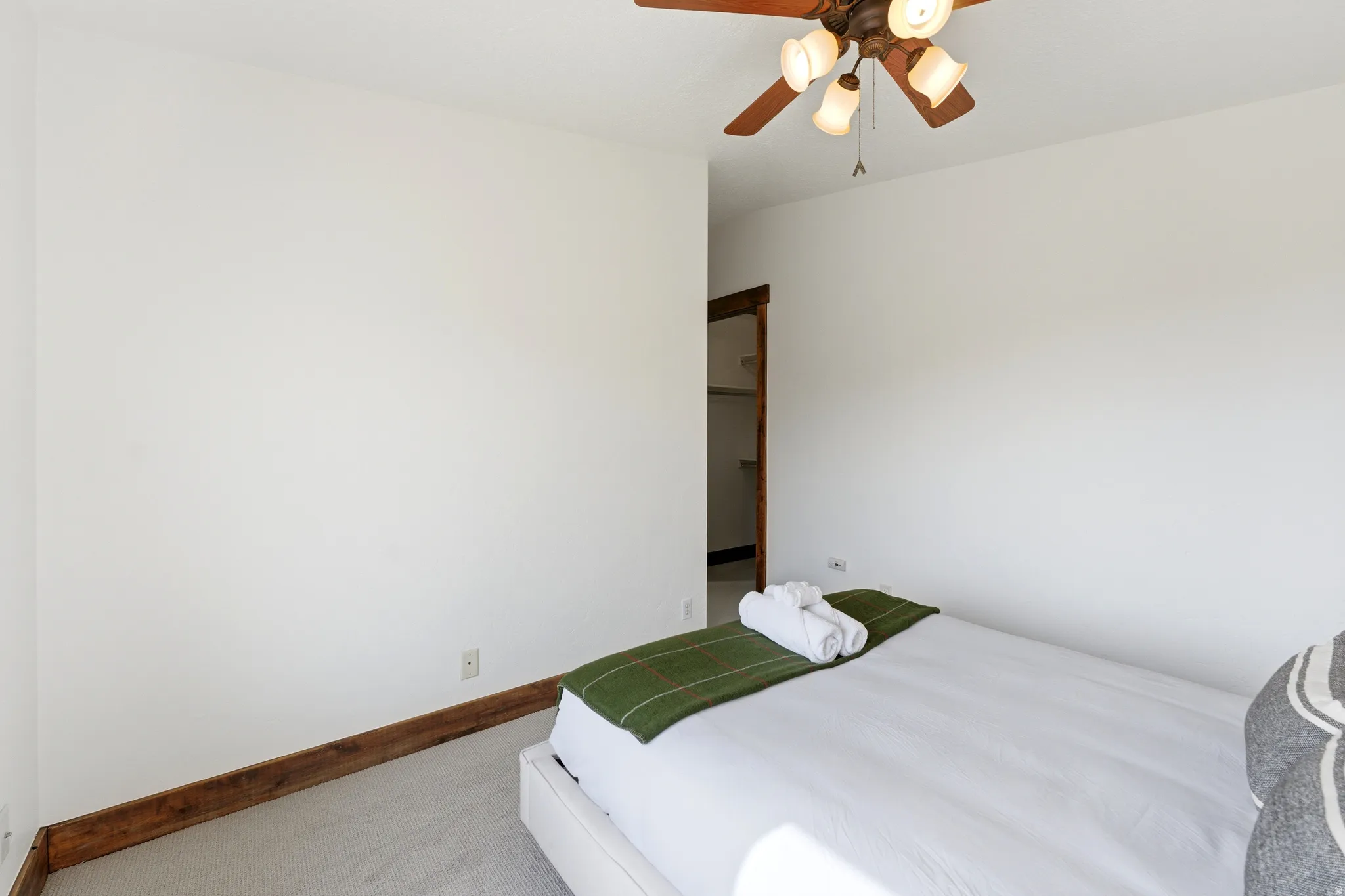 Light-filled room featuring a ceiling fan with integrated lighting, wood-finish trim, and carpeted flooring