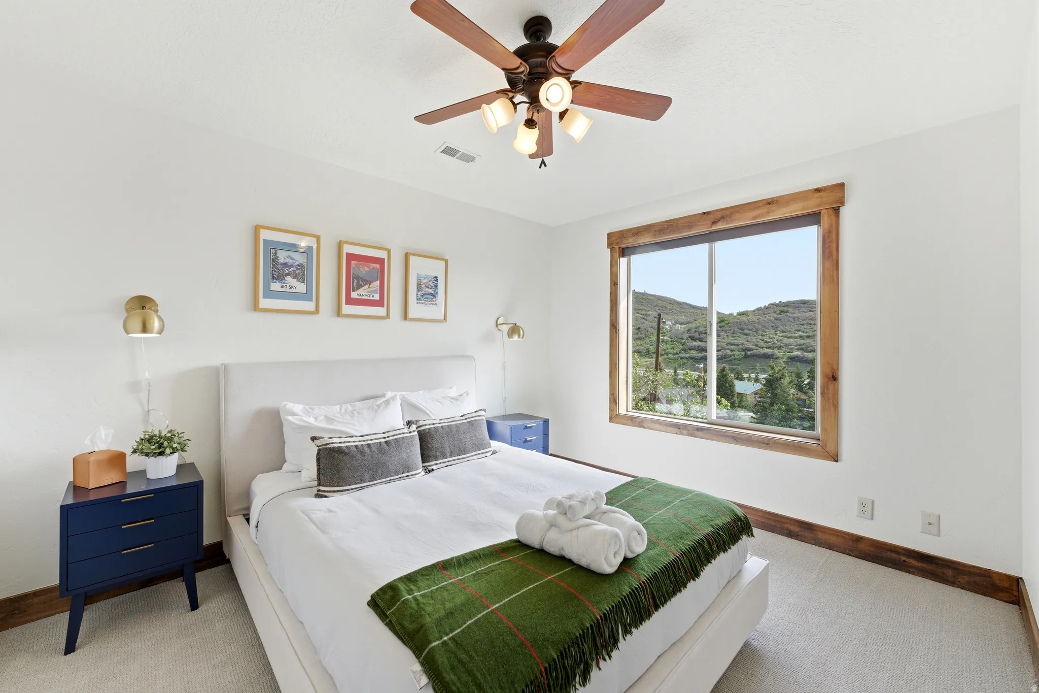 Room featuring a ceiling fan with integrated lighting, a window with wood-finish trim, and wall-mounted sconces