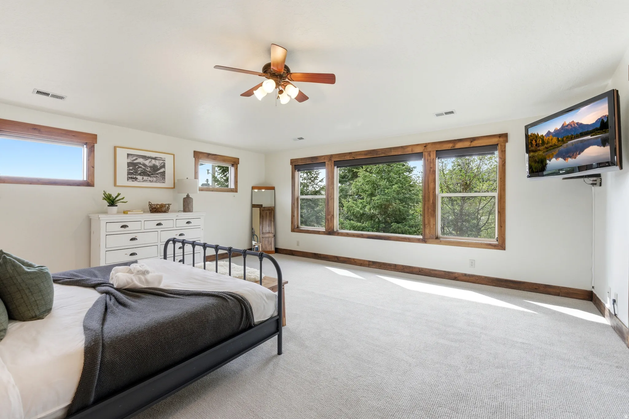 Spacious bedroom featuring light-toned carpeting, white walls, and extensive wood trim around windows and baseboards