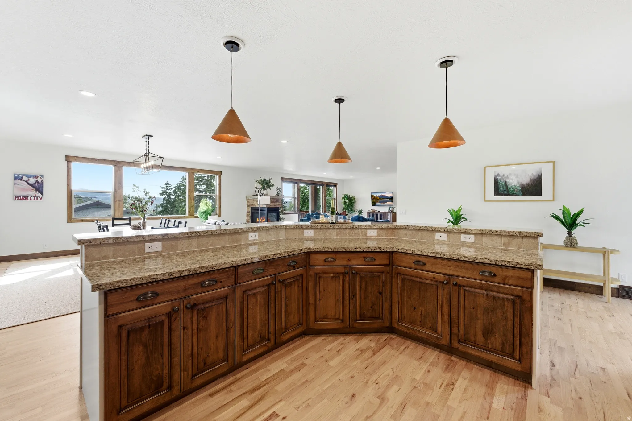 Open-concept living area with a large kitchen island featuring a granite countertop and wood cabinetry