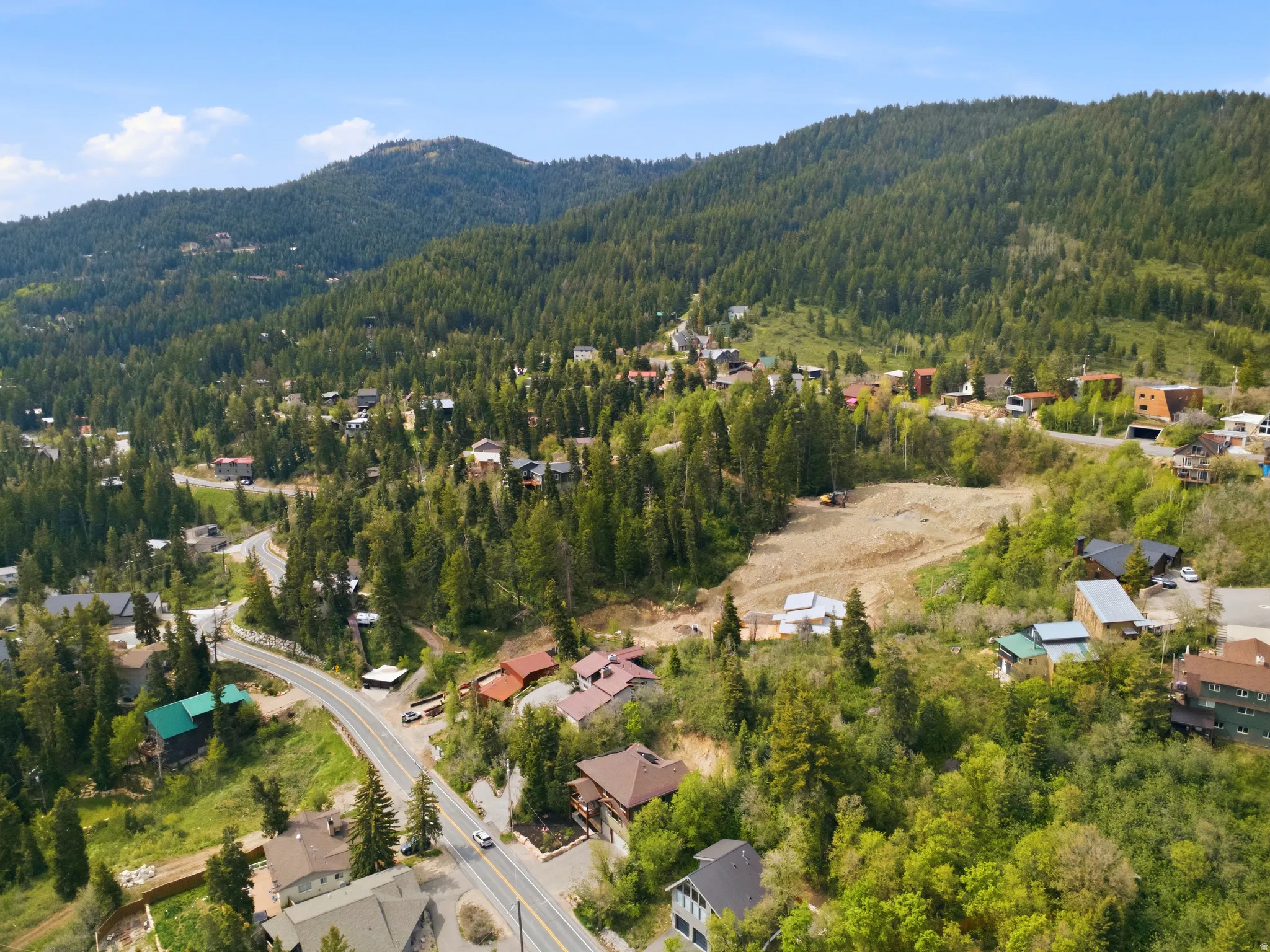 Mountainous terrain with dense evergreen forests and scattered residential properties