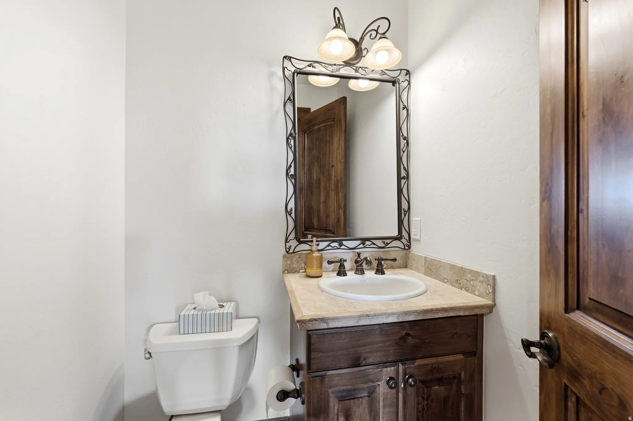 Bathroom vanity featuring a natural stone countertop, undermount sink, and dark wood cabinetry