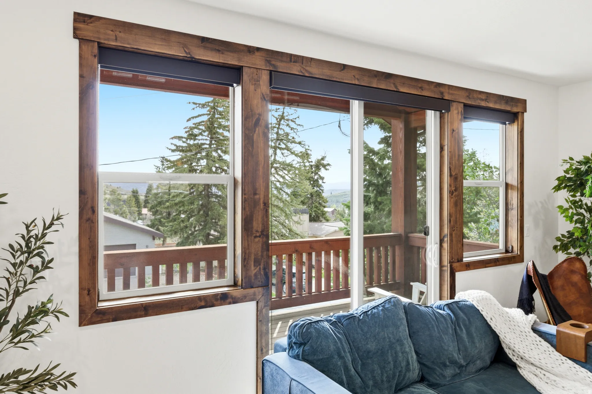 Expansive window wall with rustic wood trim framing, featuring a sliding glass door to an outdoor balcony