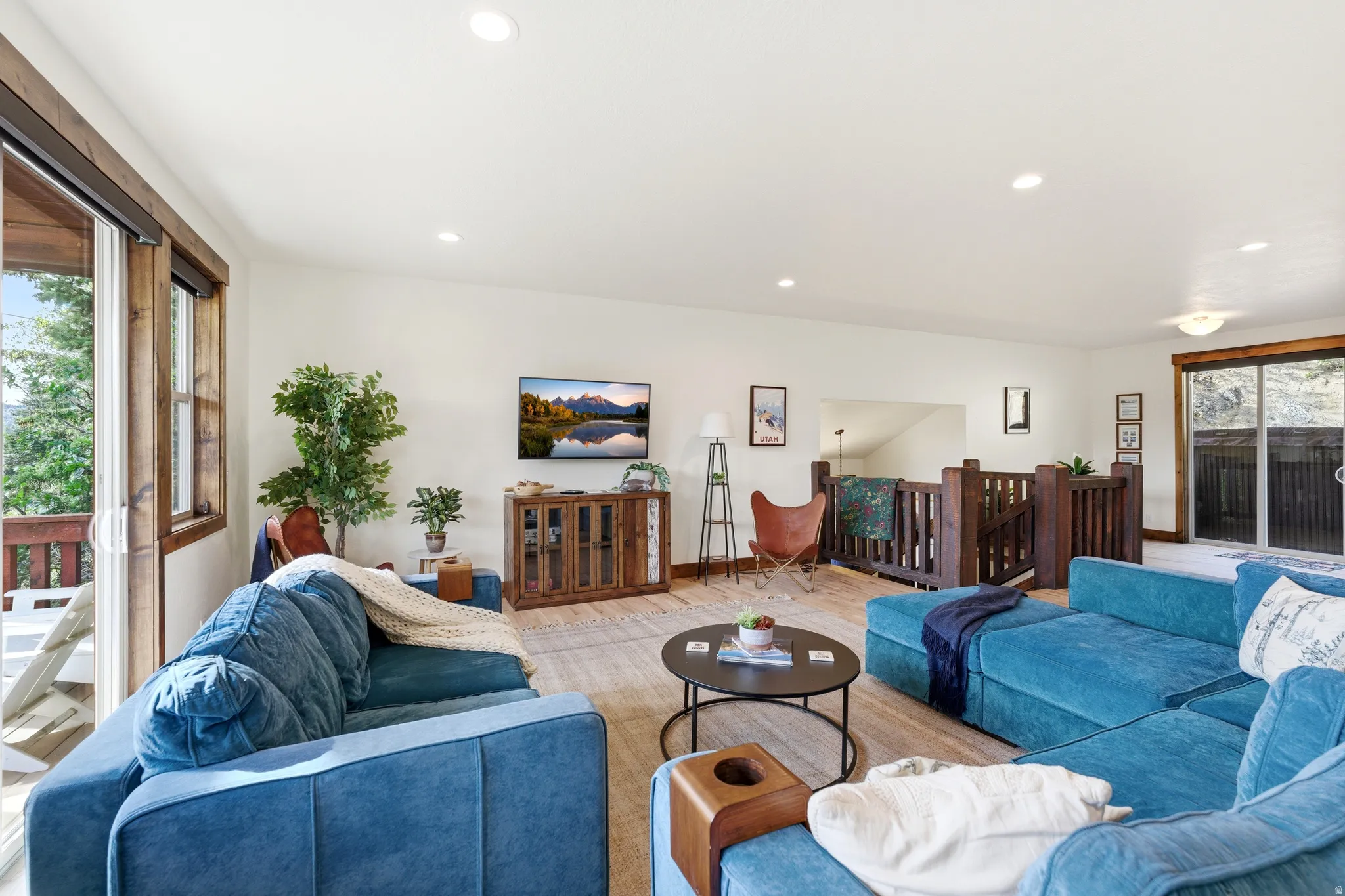 Spacious living area featuring light wood-finish flooring, a wood baluster railing system, and recessed lighting