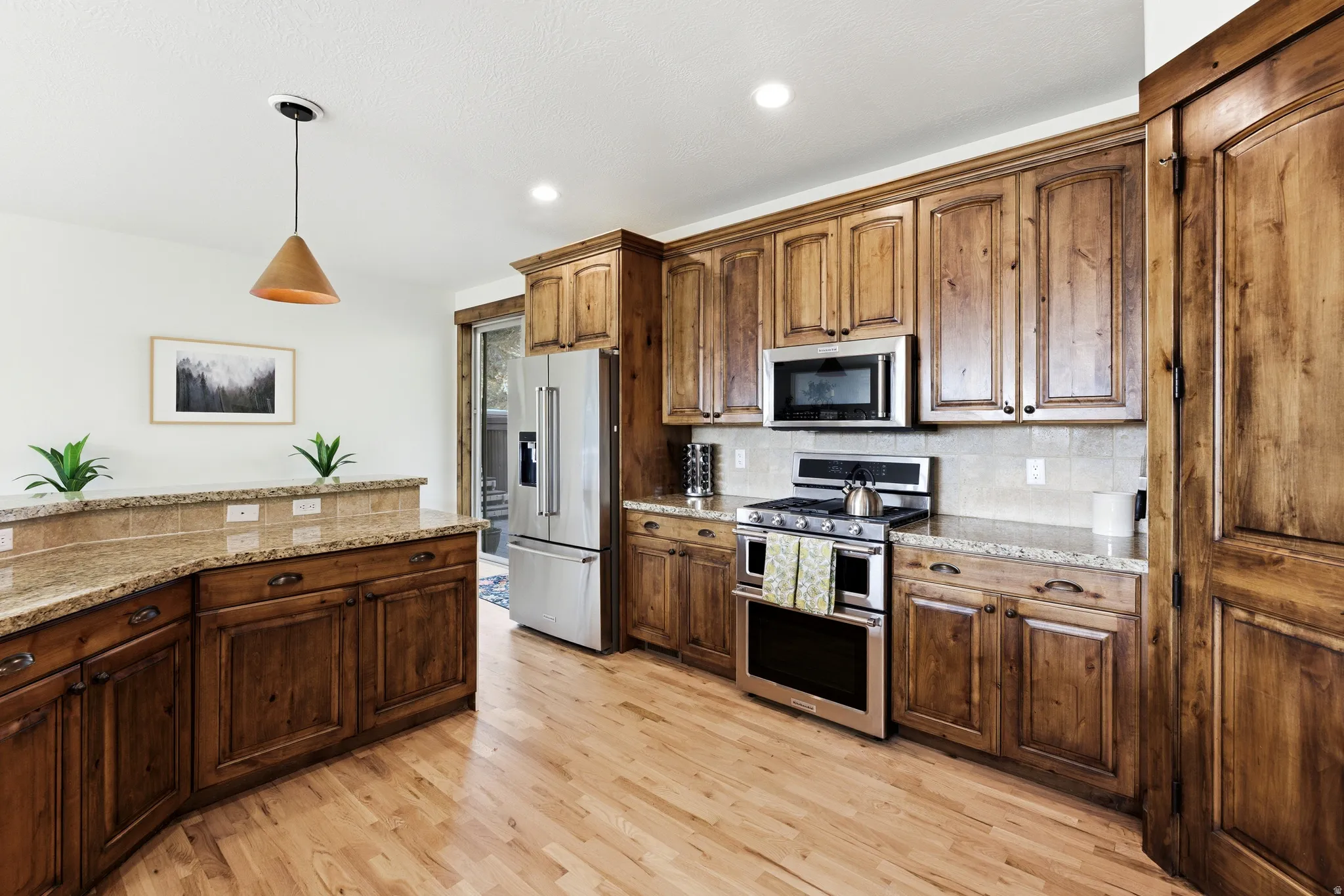 Open kitchen featuring wood-finish flooring, custom wood cabinetry, and recessed lighting