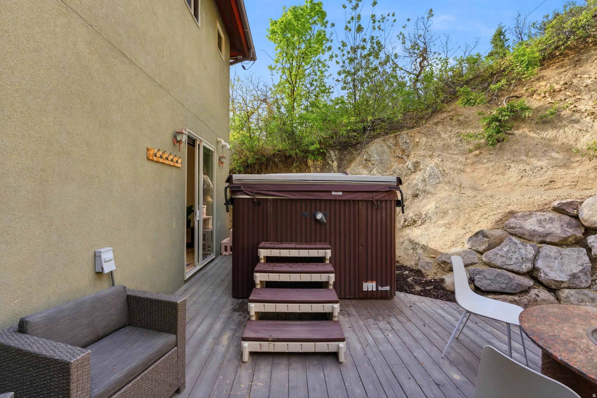 Outdoor deck featuring a built-in hot tub, wood-finish decking, and a stucco exterior