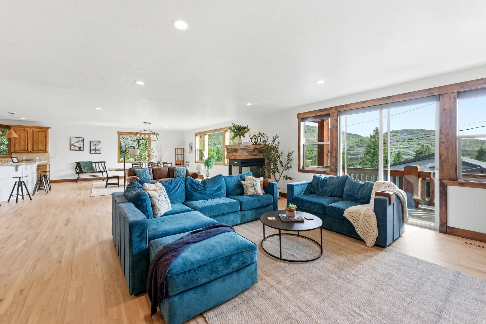 Open-concept living space featuring wood-finish flooring, recessed lighting, and a stone-clad fireplace