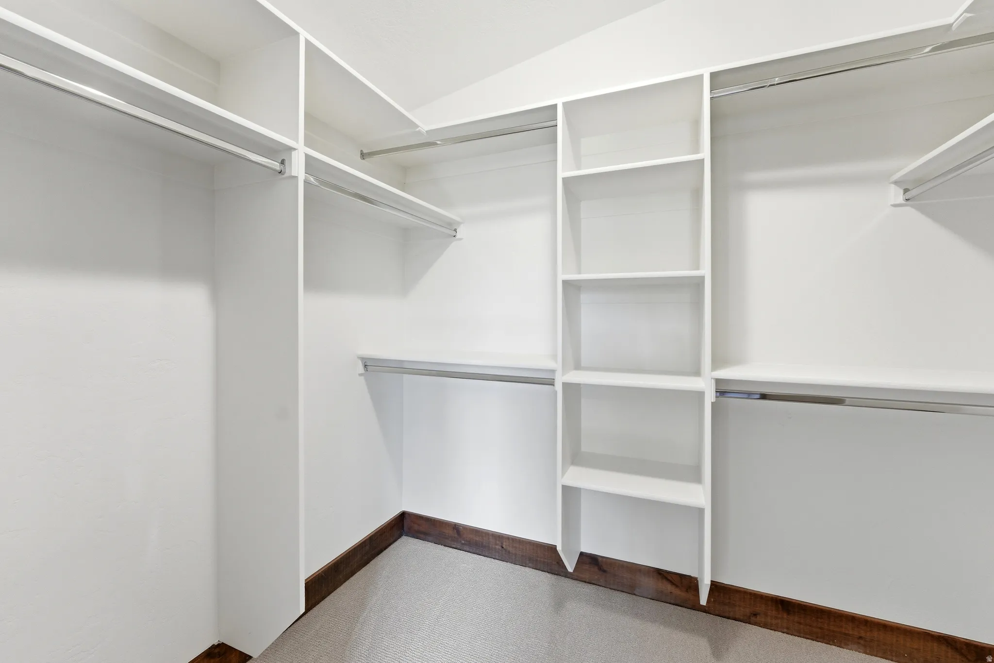 Custom closet system featuring white shelving, multiple hanging rods, and integrated storage compartments