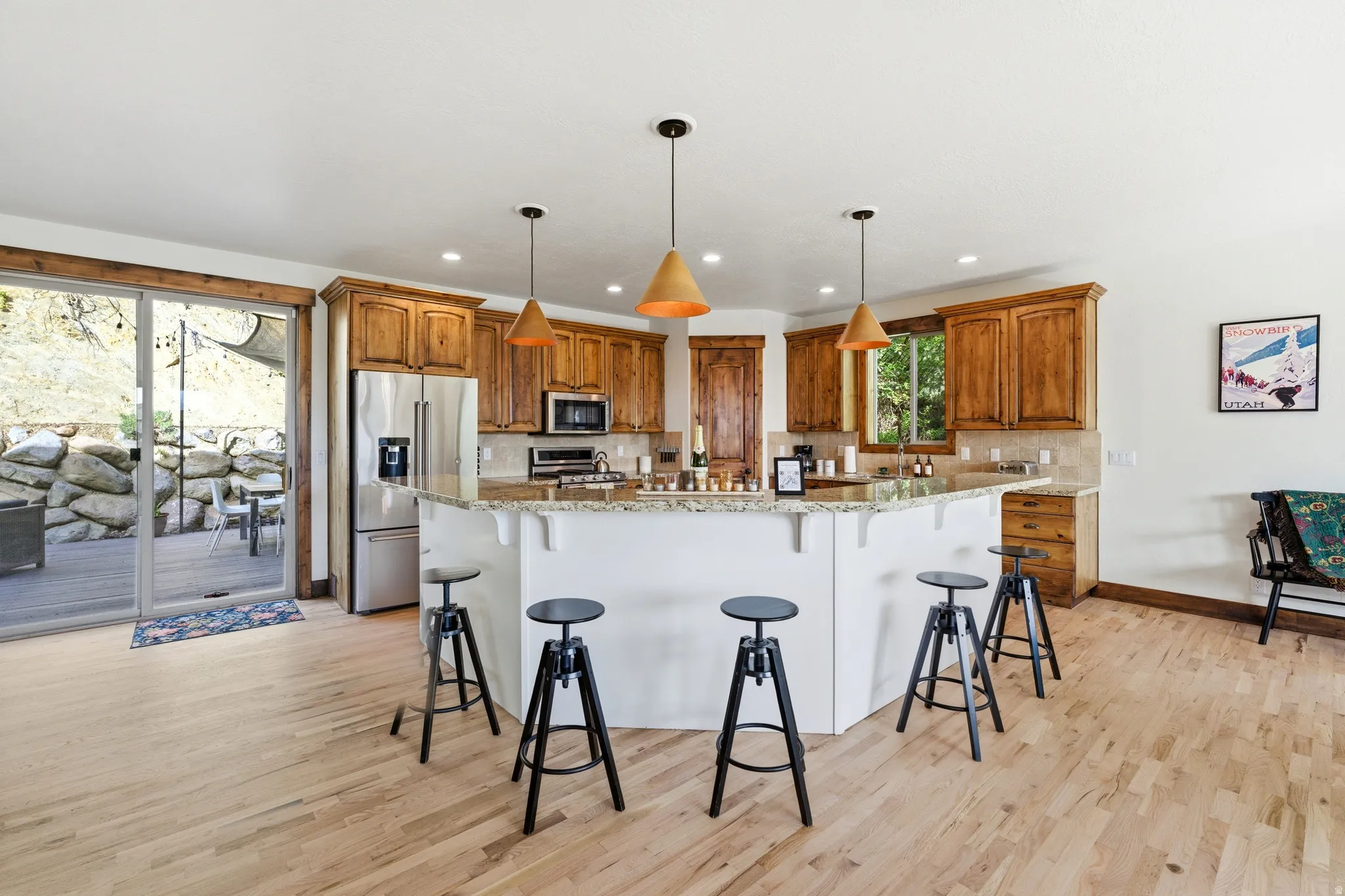 Open-concept kitchen featuring wood cabinetry, stainless steel appliances, and a large peninsula with countertop seating