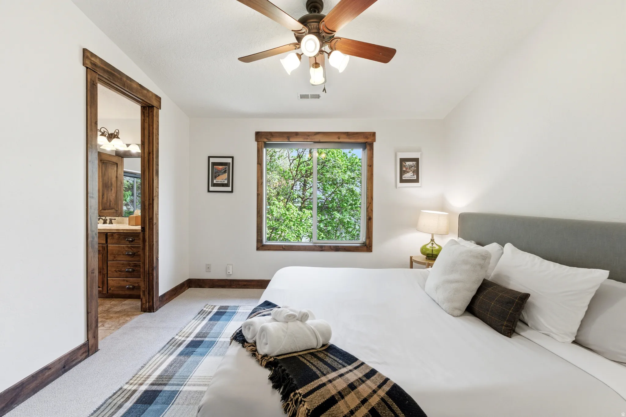 Bedroom featuring a wood-trimmed window, ceiling fan with integrated lighting, and light-toned carpeting