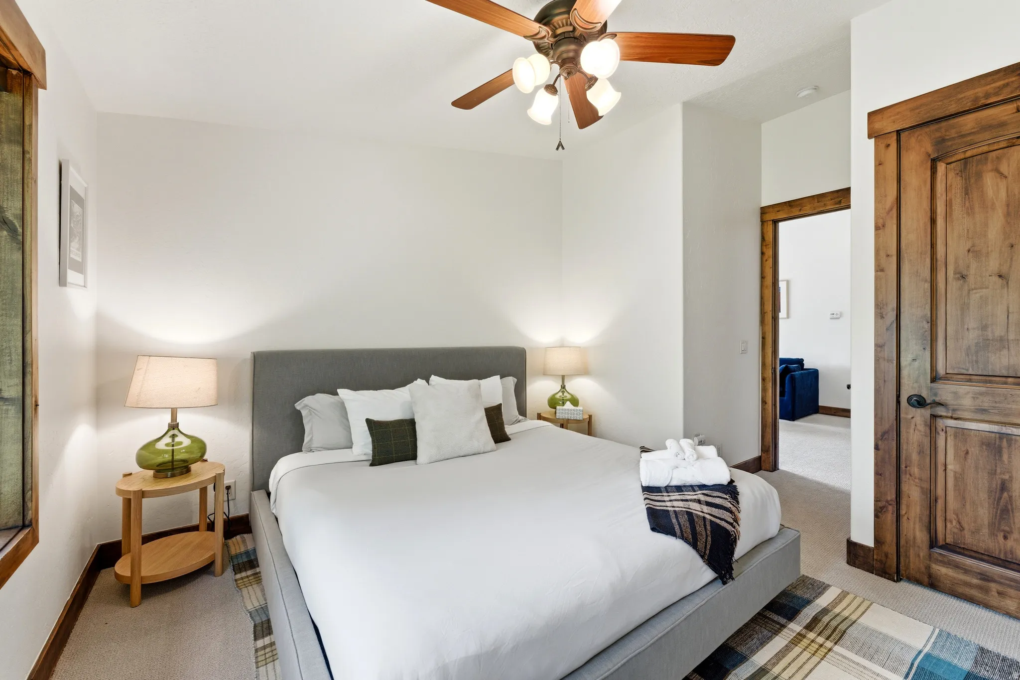 Bedroom featuring a ceiling fan with integrated lighting, wood-finish interior door, and wood-trimmed window