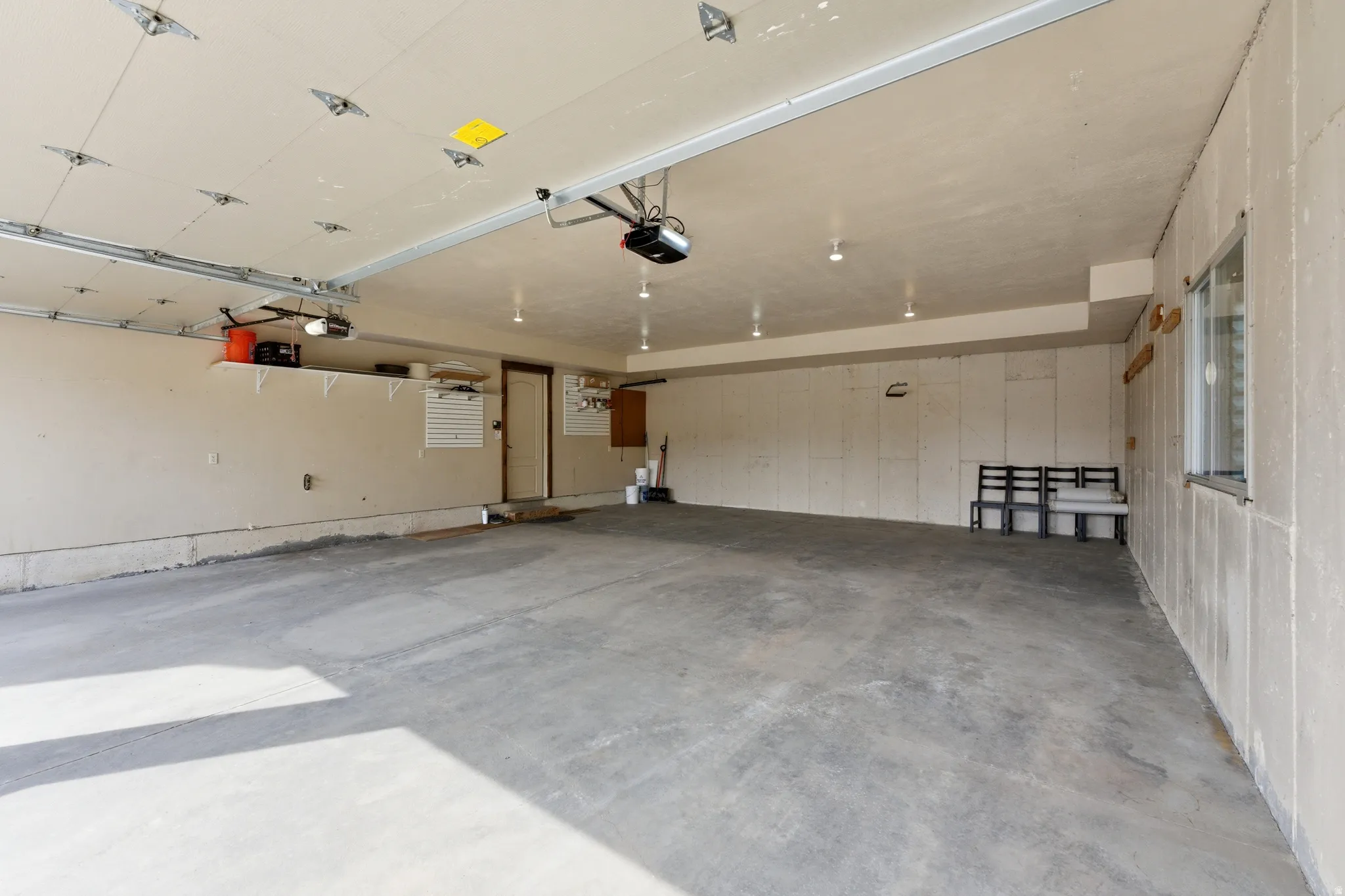 Spacious garage featuring concrete flooring, built-in shelving, a side door, and a window