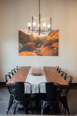 Spacious dining area featuring an industrial-style chandelier, light neutral walls, and dark flooring