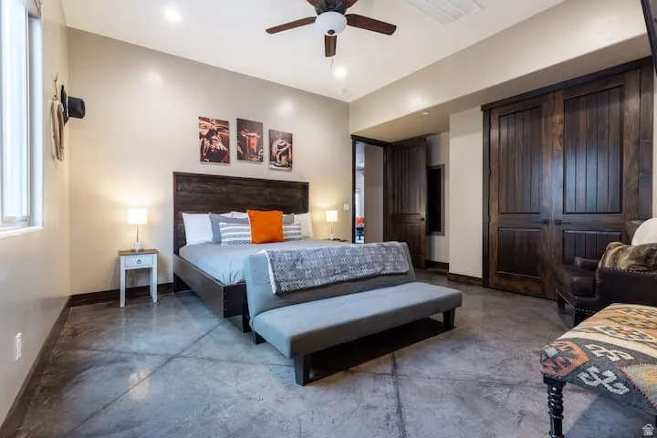Spacious room featuring rich wood-panel doors, a dark wood headboard, and polished concrete flooring