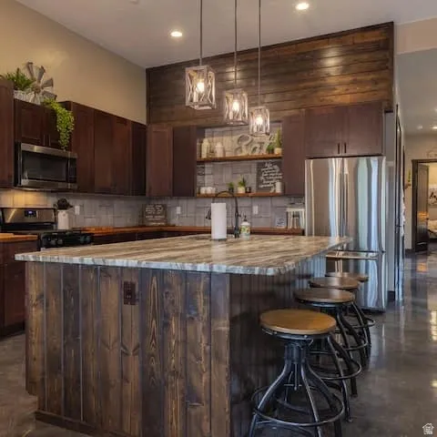 Kitchen featuring a large island with a natural stone countertop and wood-finish paneling