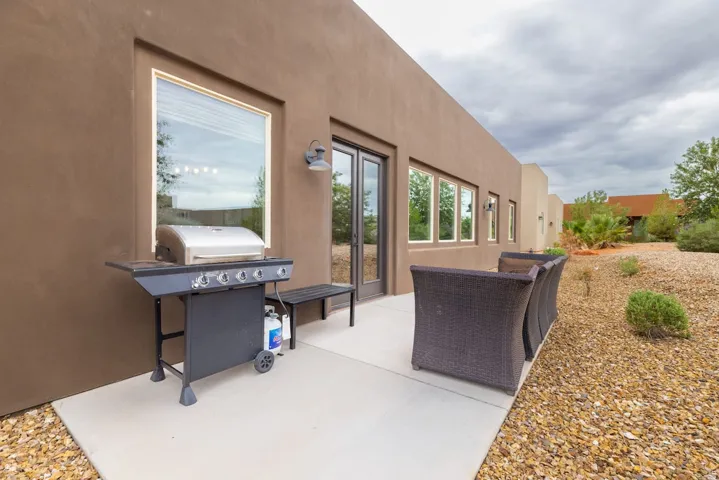 Outdoor patio featuring a concrete surface, built-in bench seating, multiple large windows, and a glass-paneled exterior door