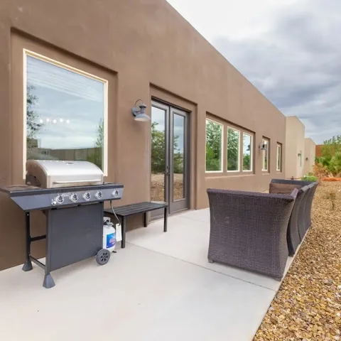 Private patio area featuring a concrete surface, a double glass door entry, multiple windows, and exterior wall sconces