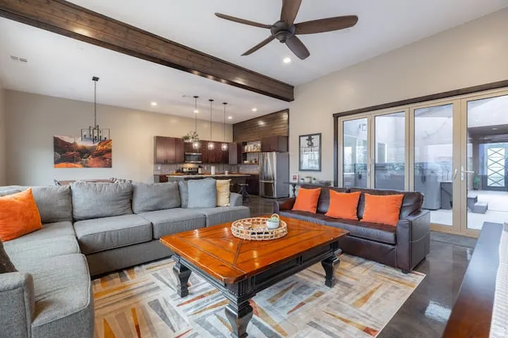 Open-concept living space with exposed wood-finish ceiling beams, recessed lighting, and a dark wood-finish ceiling fan