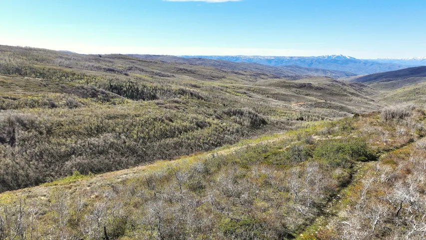 Expansive mountain landscape featuring rolling terrain and distant snow-capped peaks