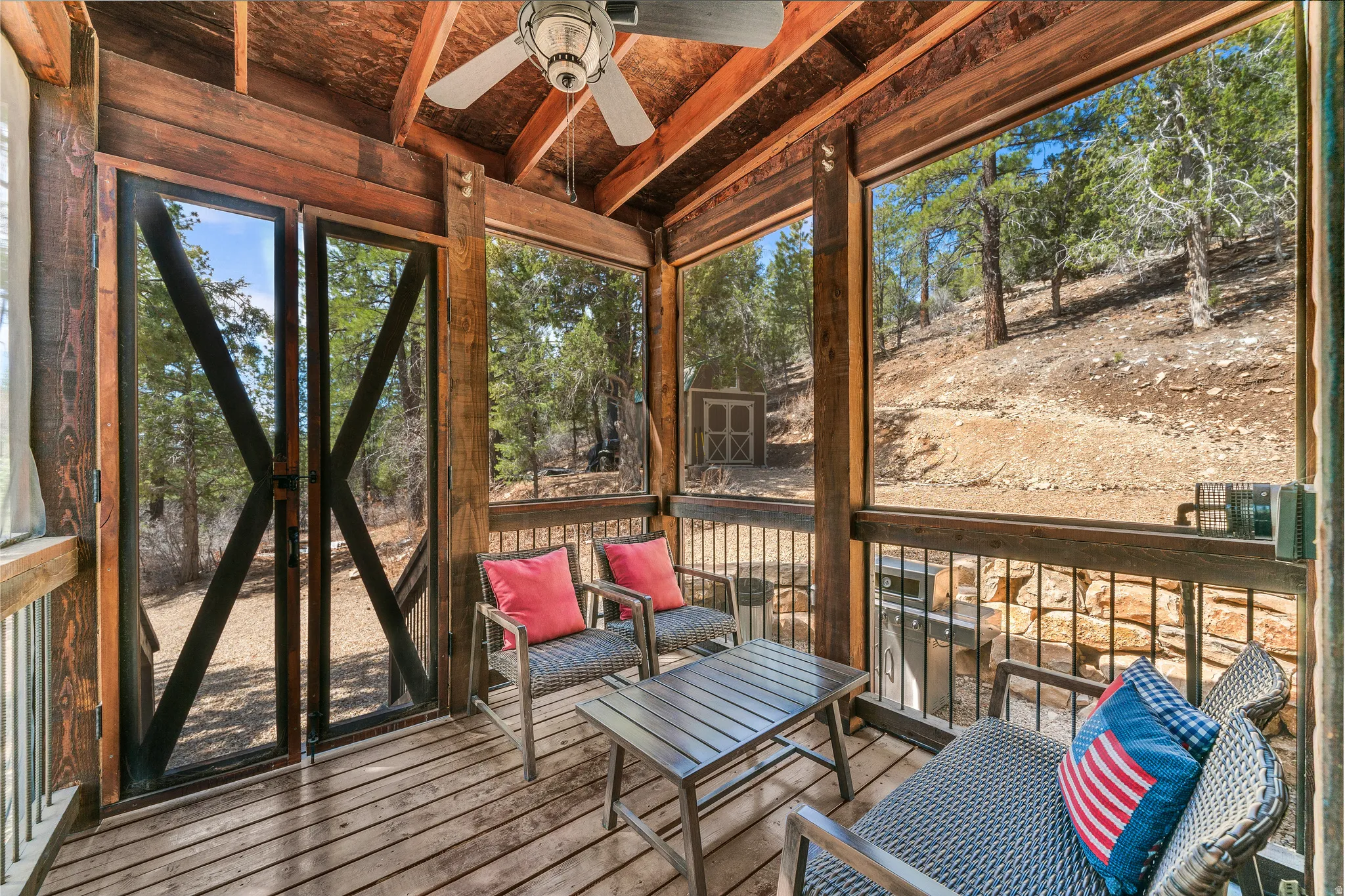 Screened outdoor living area featuring wood-finish flooring and ceiling with a central ceiling fan