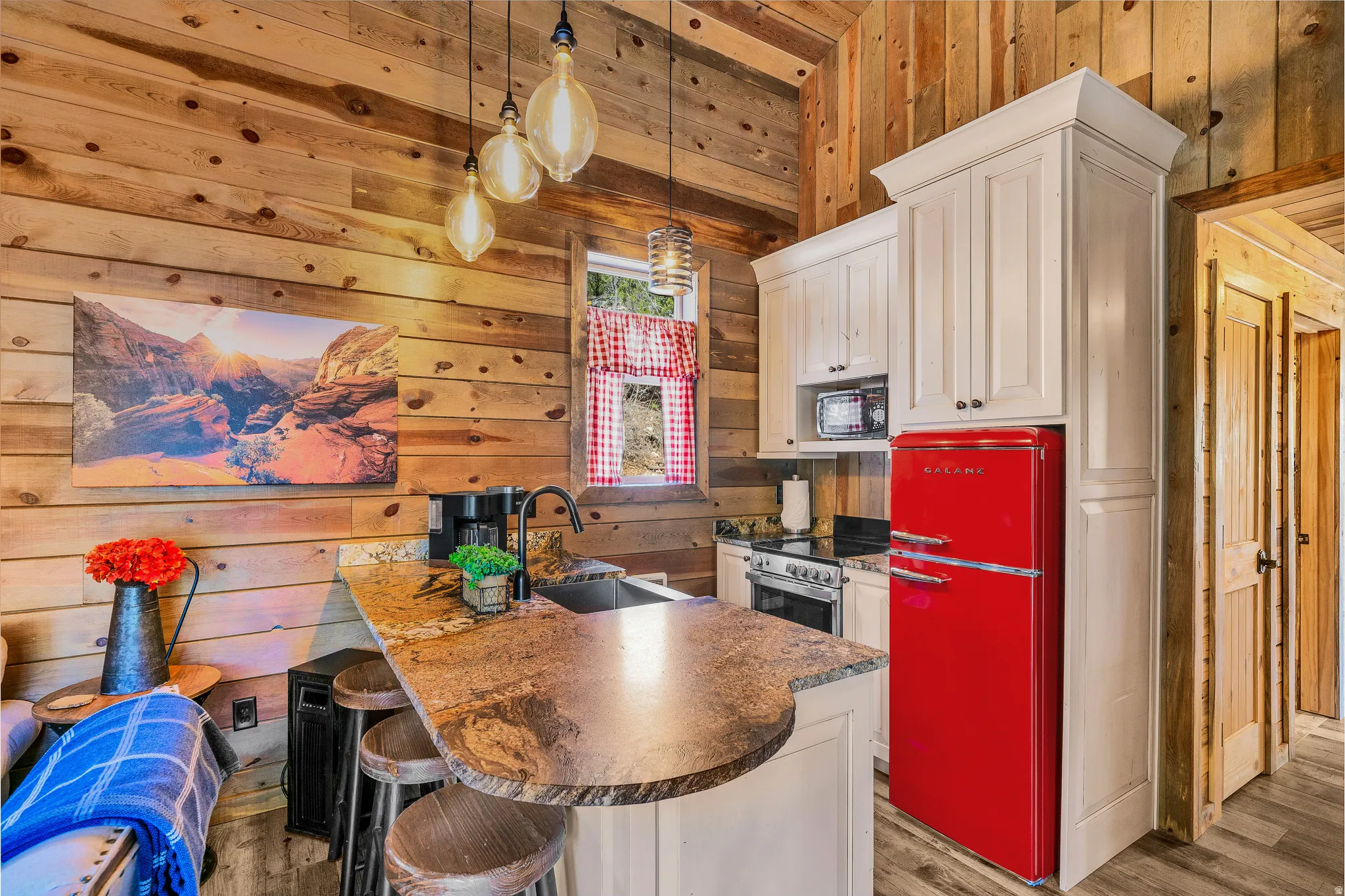 Compact kitchen featuring a granite-look breakfast bar with seating, a red retro-style refrigerator, and a stainless steel range
