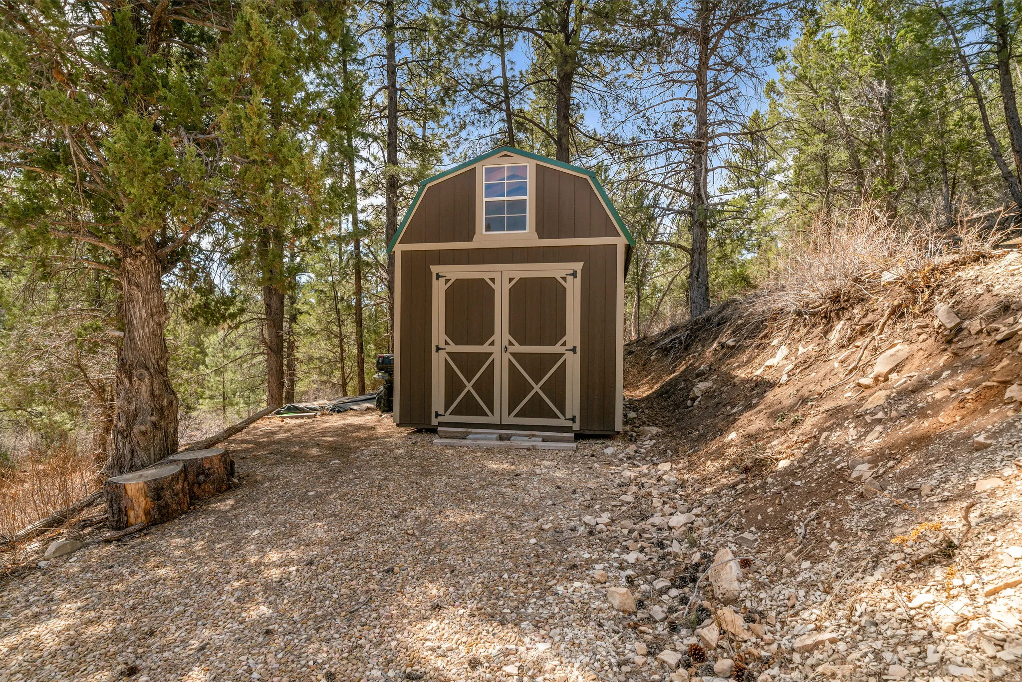 Freestanding utility shed featuring a gambrel roof and double barn doors