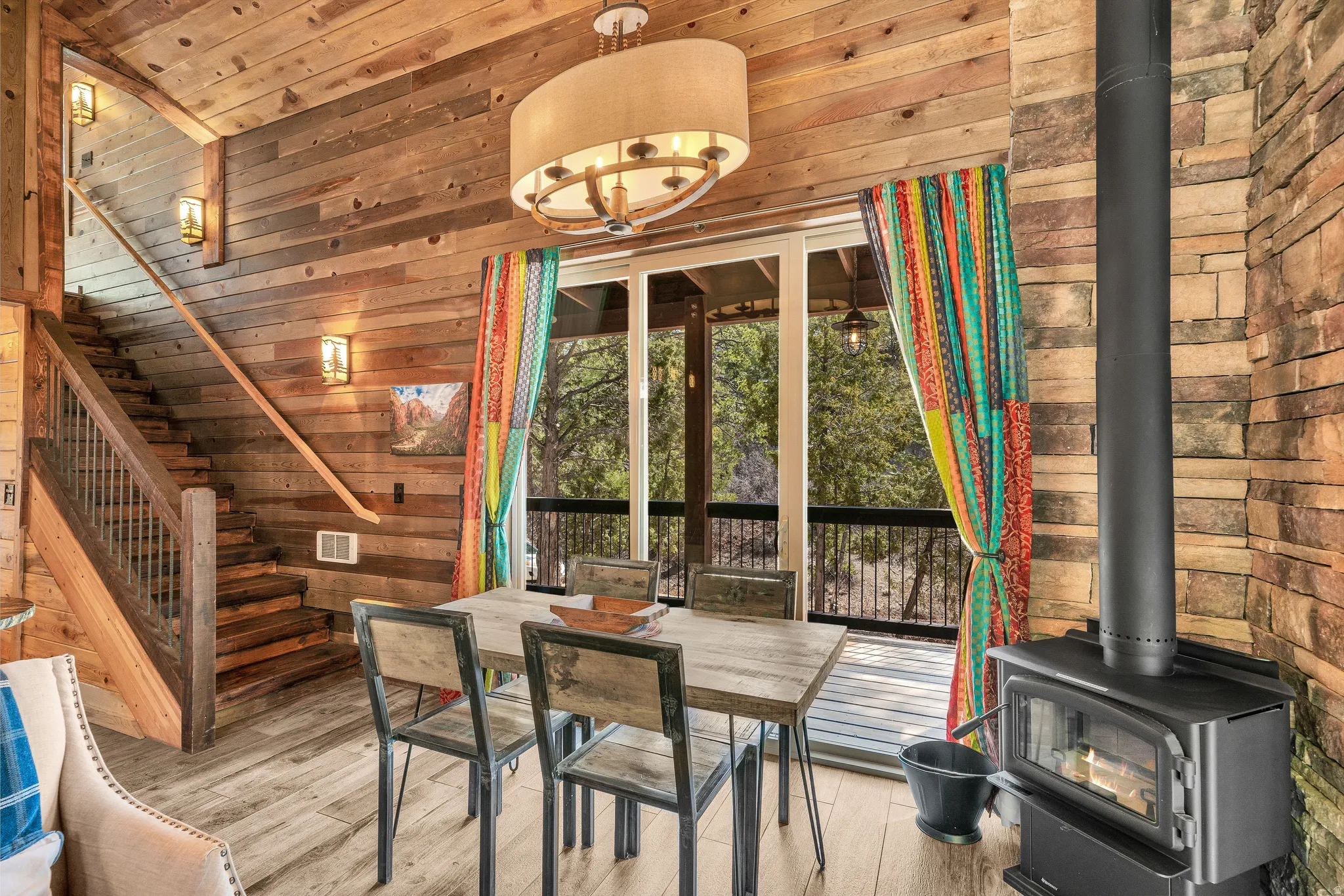Open-concept living area with a built-in wood-burning stove, wood-finish flooring, and natural wood plank walls
