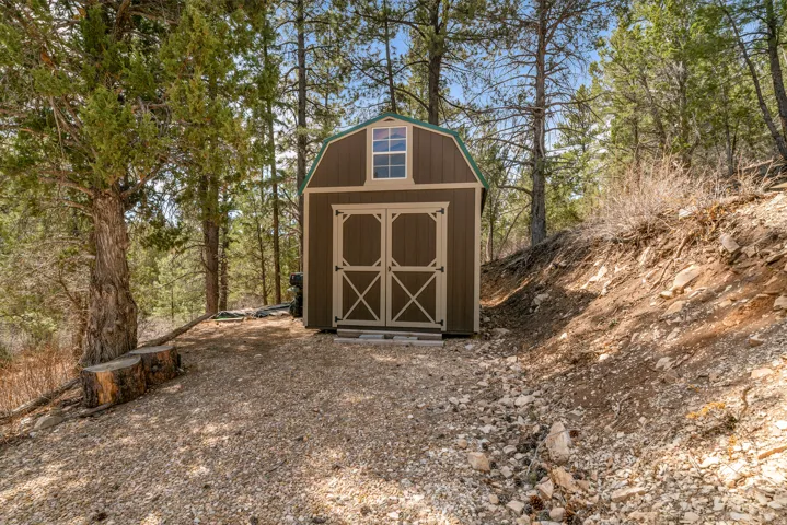 Freestanding utility shed featuring a gambrel roof and double barn doors