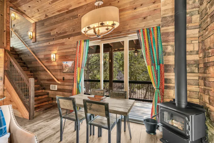 Open-concept living area with a built-in wood-burning stove, wood-finish flooring, and natural wood plank walls