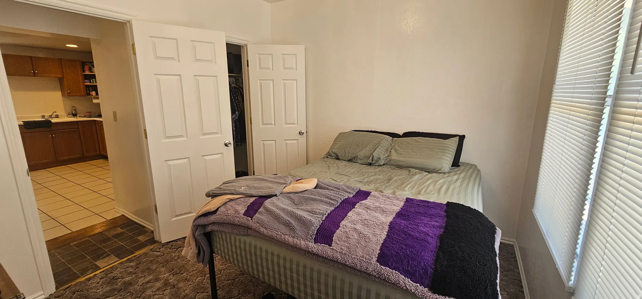 Bedroom featuring white walls, carpeting, and a window with horizontal blinds