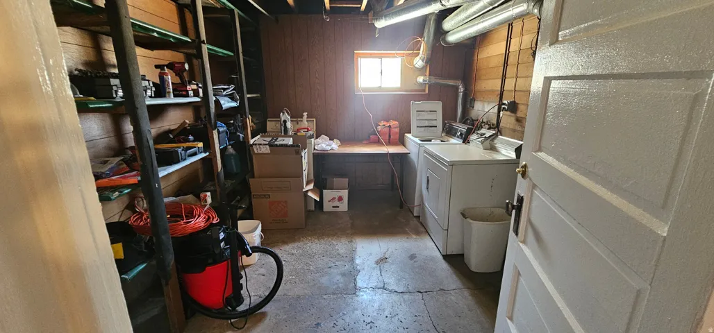 Laundry area featuring exposed ceiling joists, wood paneling, and a small window