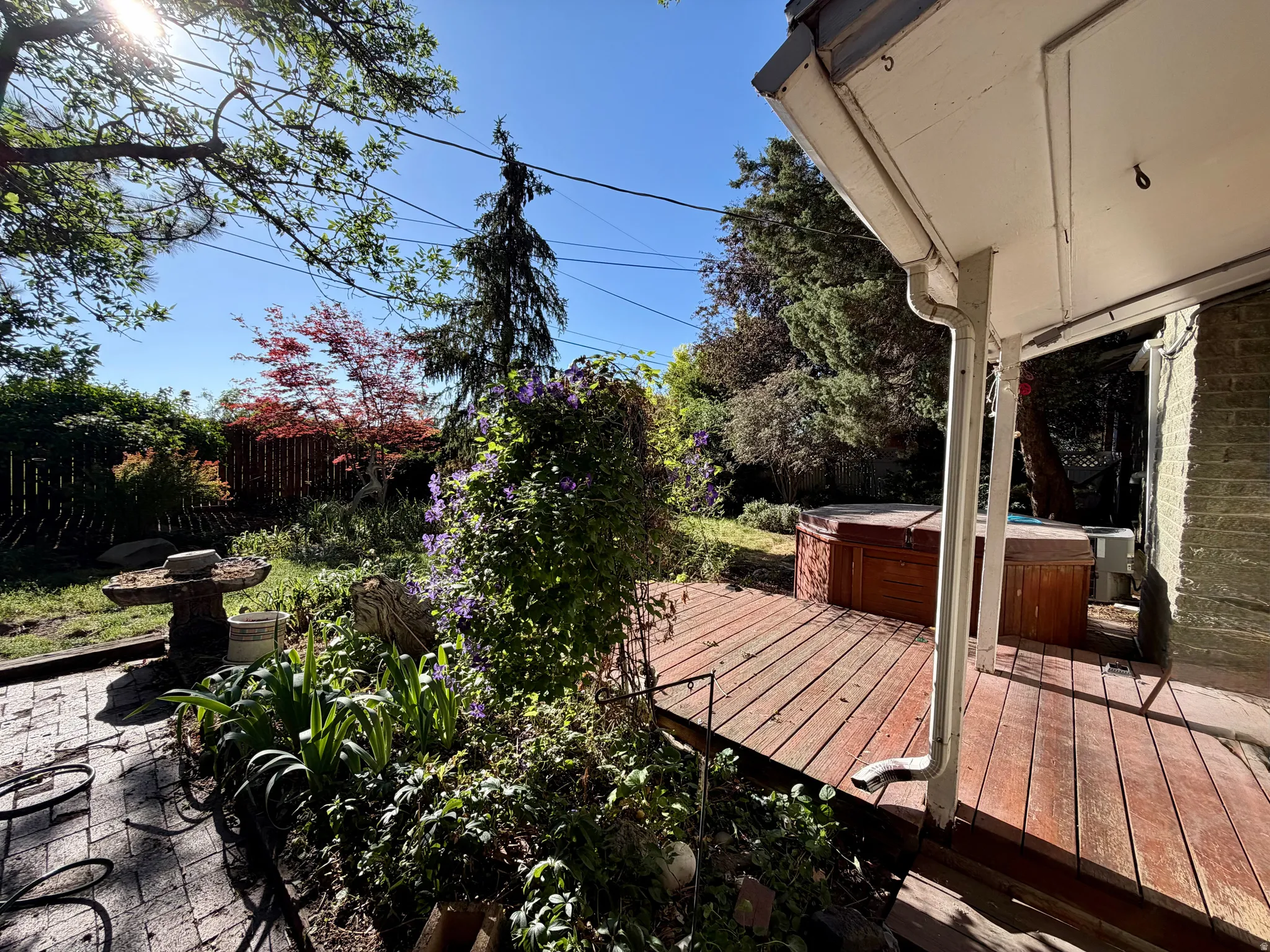 Expansive backyard featuring a wood deck, hot tub, and brick paver patio