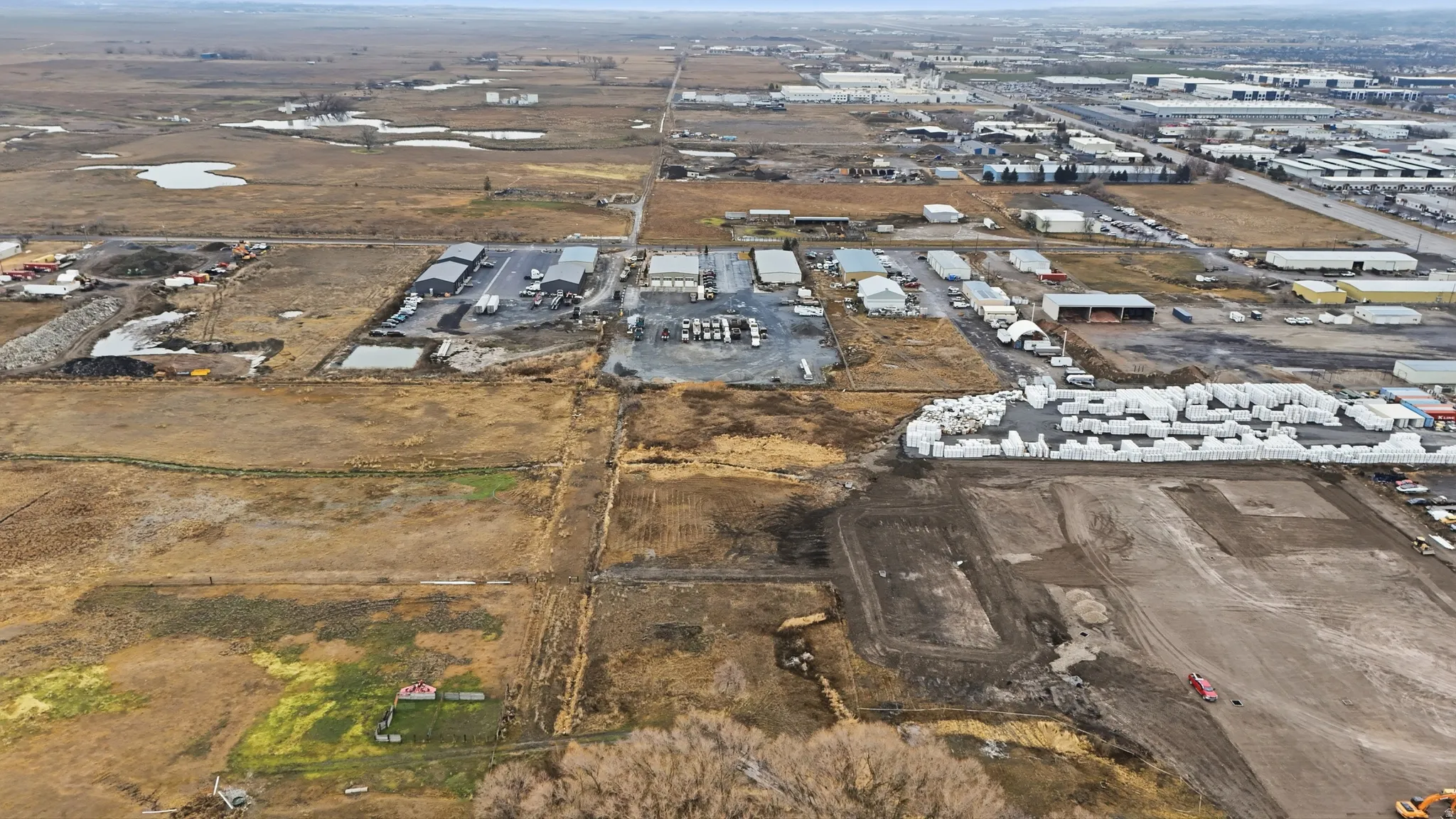 Expansive undeveloped land parcels with visible grading and existing commercial structures